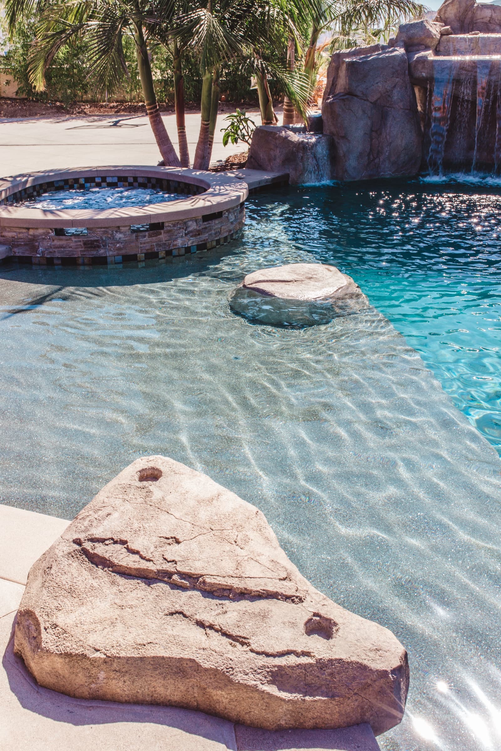 Custom pool with rock waterfall, spa, and palm trees in San Diego